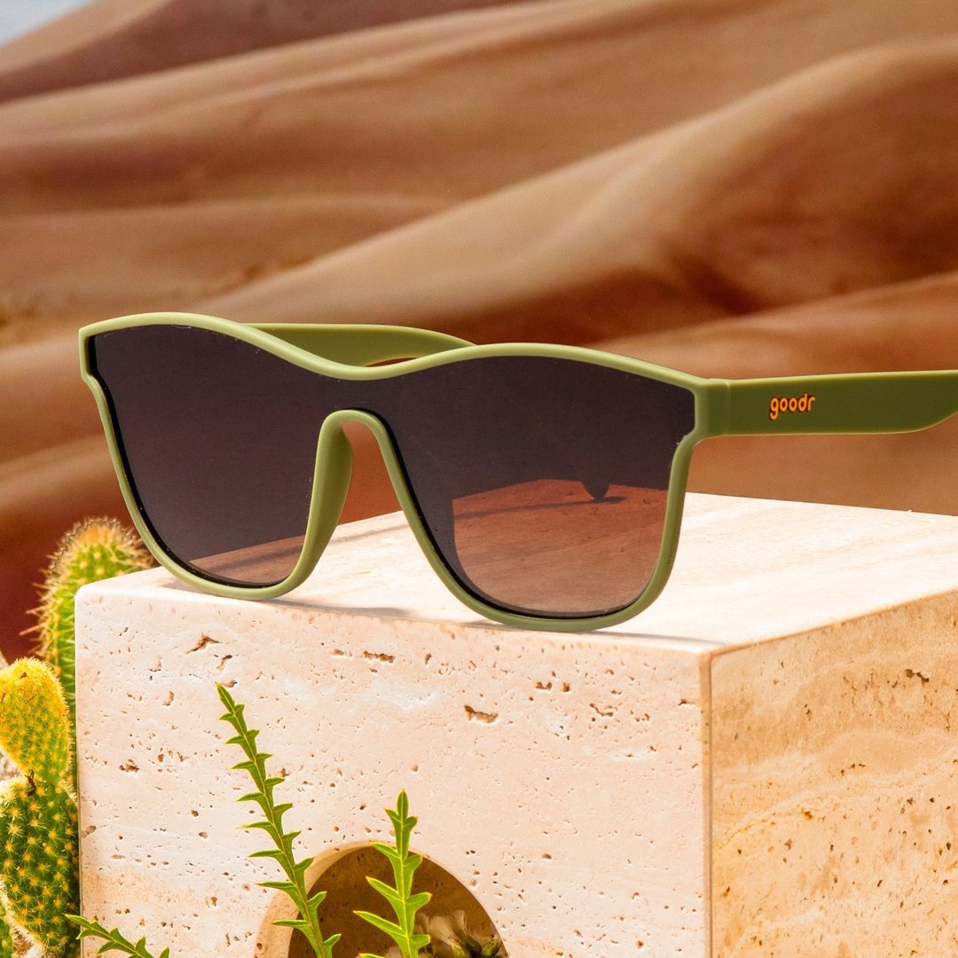 Green sunglasses with 'goodr' logo on a desert background